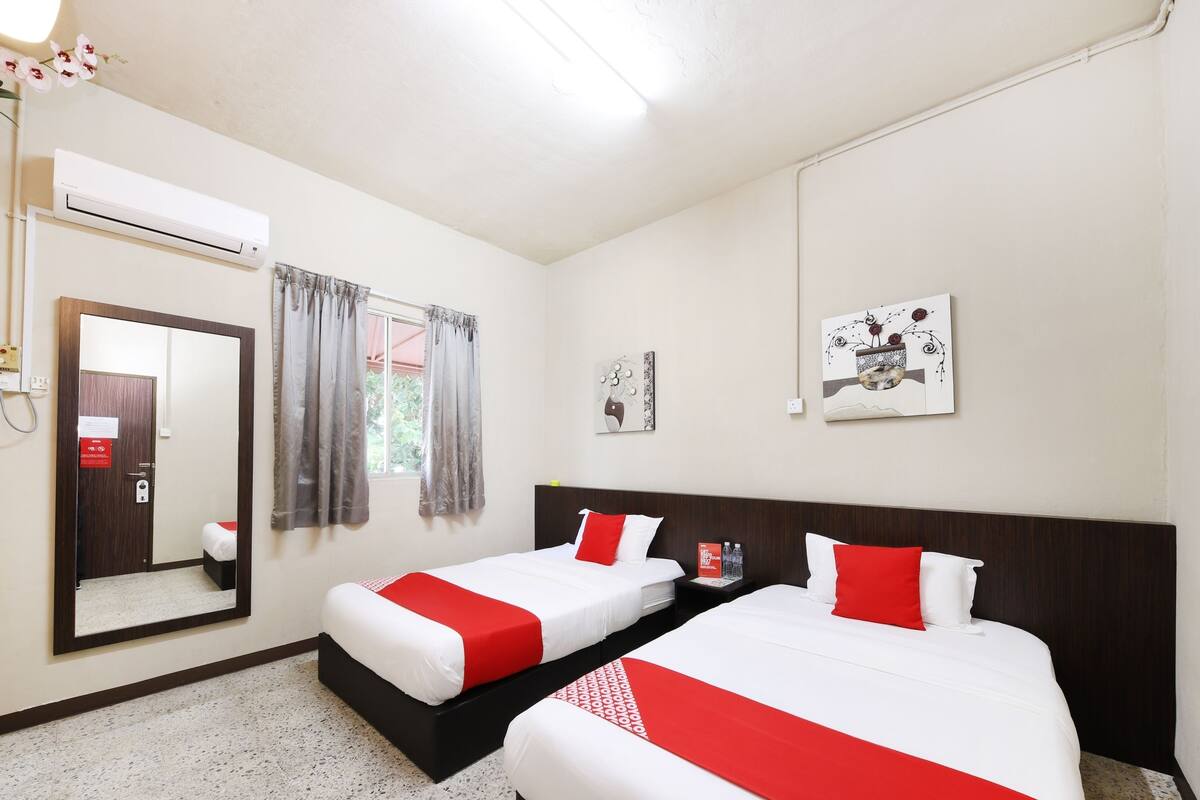 Een hotelkamer met twee bedden, een grote spiegel, een airconditioning en kunstwerken aan de muur.