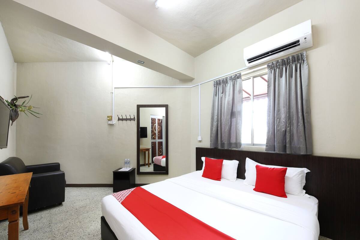 Een hotelkamer met een groot bed, een bureau, een stoel, een spiegel en een airconditioning.