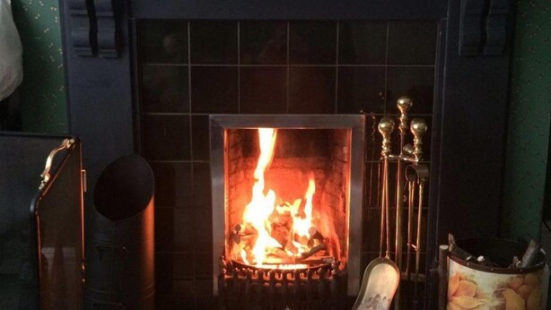 Una chimenea con fuego encendido, rodeada por un revestimiento de azulejos.