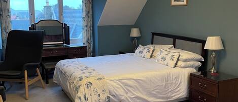 A bedroom with a bed, two bedside tables, a desk, and a chair.