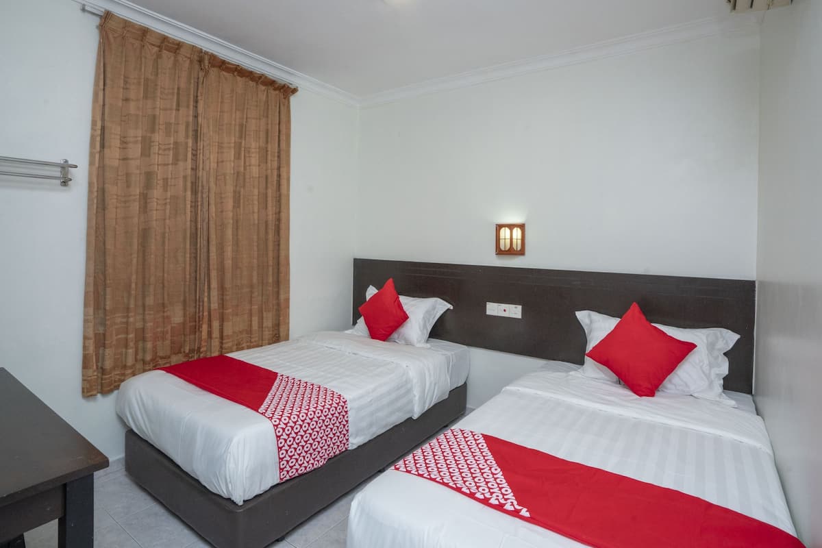 A hotel room with two single beds, a nightstand, a desk, and a window with curtains.