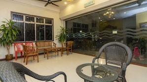 A lobby with a ceiling fan, a chandelier, a glass door with a wavy pattern, and several wicker chairs and tables. - Fully Hotel Desa Tebrau (Johor Bahru)