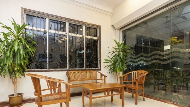 A room with a wooden table and chairs, two potted plants, a large window with metal bars, and a glass door leading outside. - Fully Hotel Desa Tebrau (Johor Bahru)