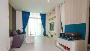 A modern living room with a sofa, a TV, and a storage unit with luggage. - The Twin B Palace Hotel & Apartments (Phnom Penh)