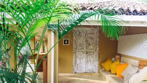 A covered outdoor area with a wooden door, a number '4' sign, and a seating area with cushions. - Five (Morakatiyara)