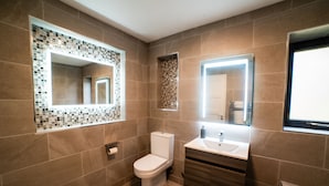 Et moderne badeværelse med toilet, vask og spejl.