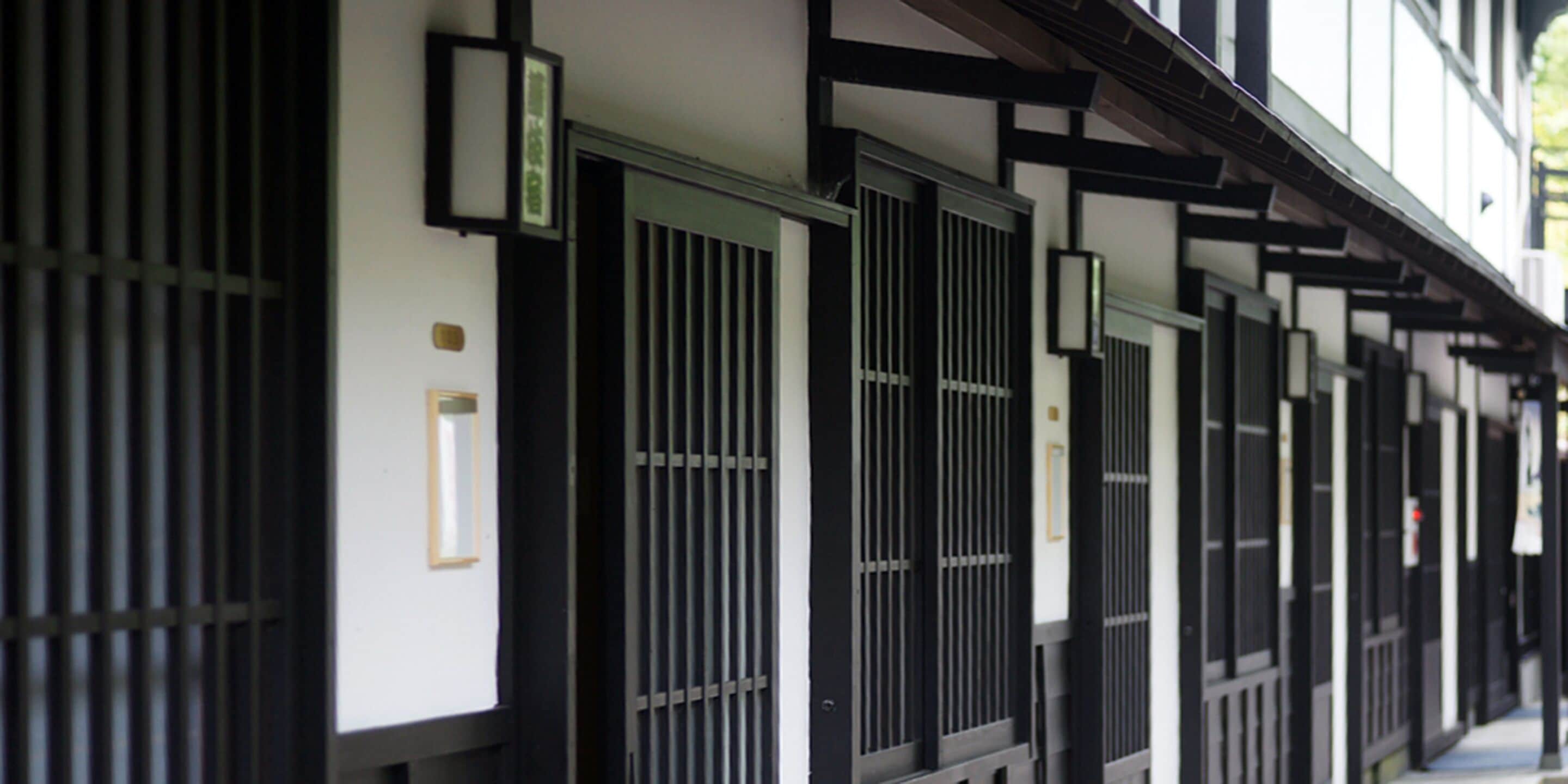 A row of traditional Japanese-style buildings with sliding doors and black metal grilles.