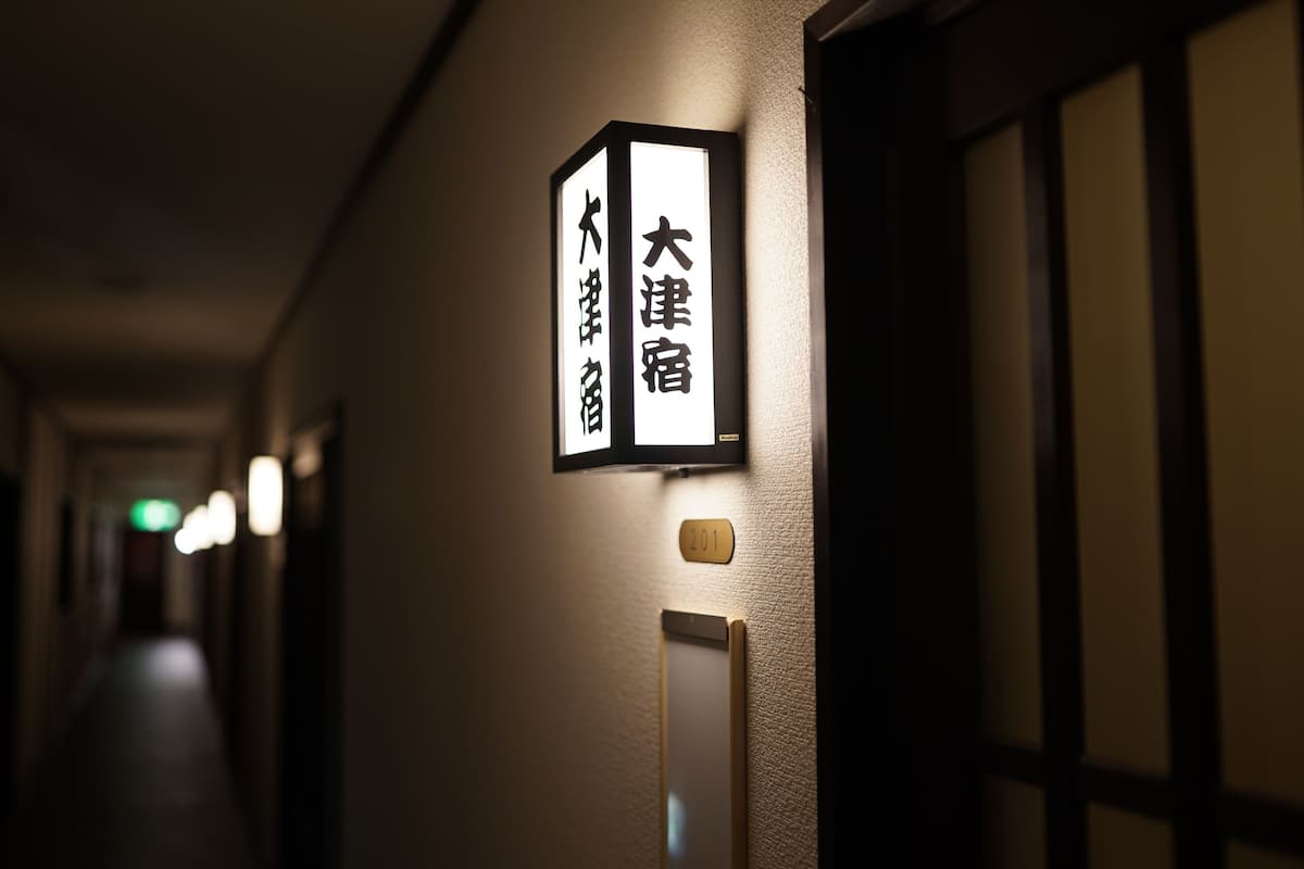 A hallway with a sign indicating room number 201 and the name '大津宿' (Otsujo).