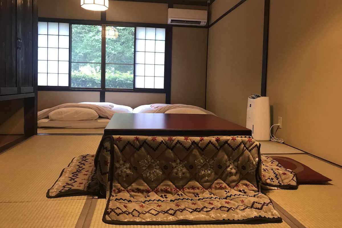 A traditional Japanese room with tatami flooring, a low wooden table, and a futon bed.