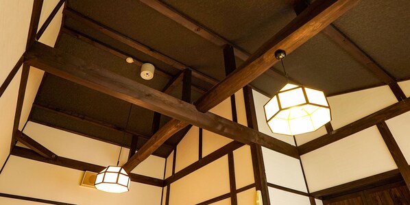 A room with exposed wooden beams and traditional Japanese-style paper lanterns hanging from the ceiling.