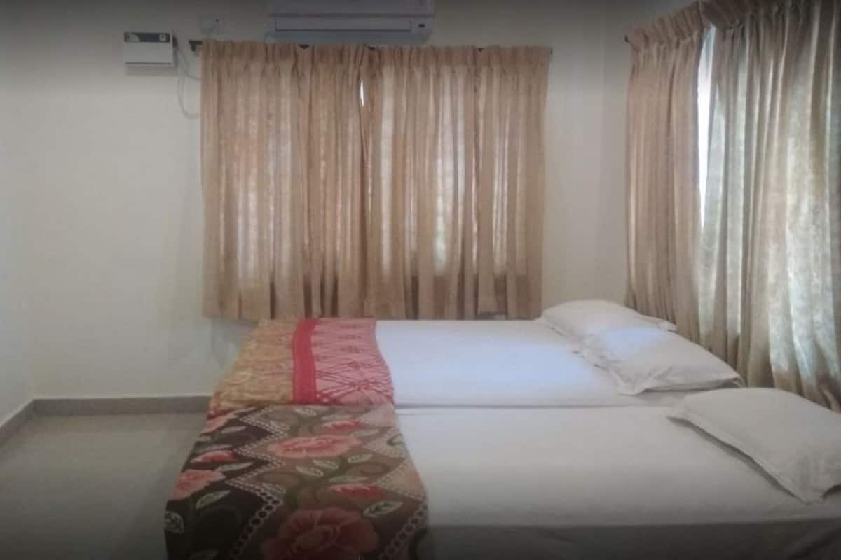 A room with a bed, a bedside table, and a window with curtains.