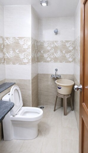 A bathroom with a toilet, sink, and shower. - Krishna INN (Chennai)