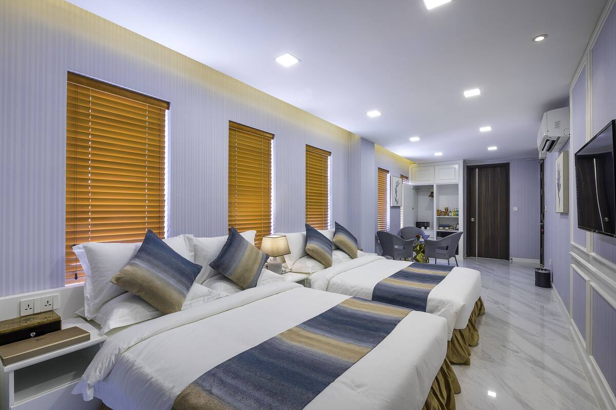A hotel room with two beds, a desk, a chair, a TV, and a bathroom.