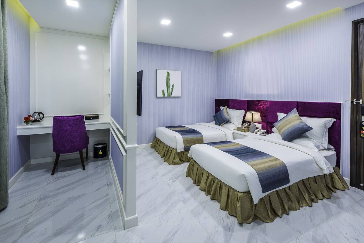 A hotel room with two beds, a desk, and a chair.