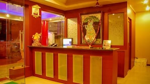A reception desk with a clock, a framed picture, and a statue. - Krishna International (Chennai)