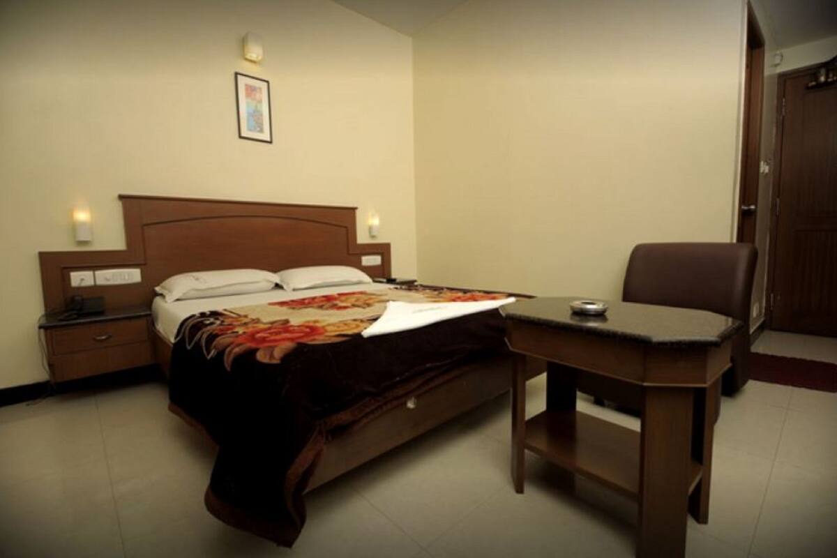 Una habitación de hotel con una cama, mesitas de noche, un escritorio y una silla.