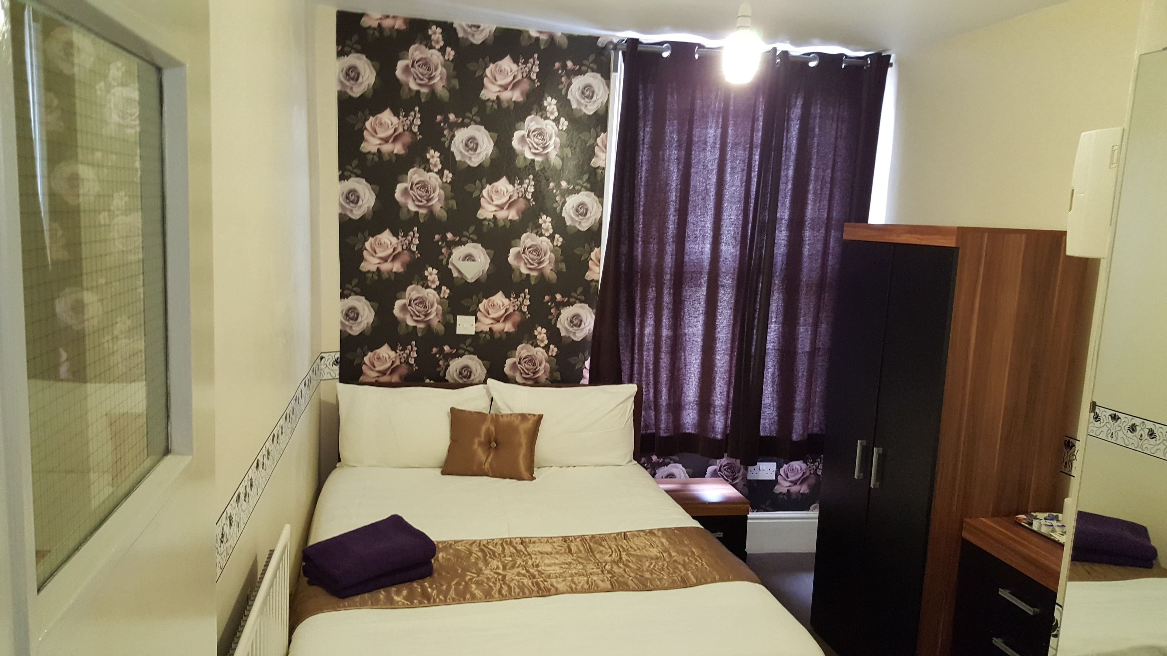 Un dormitorio con cama, armario y ventana con cortinas.