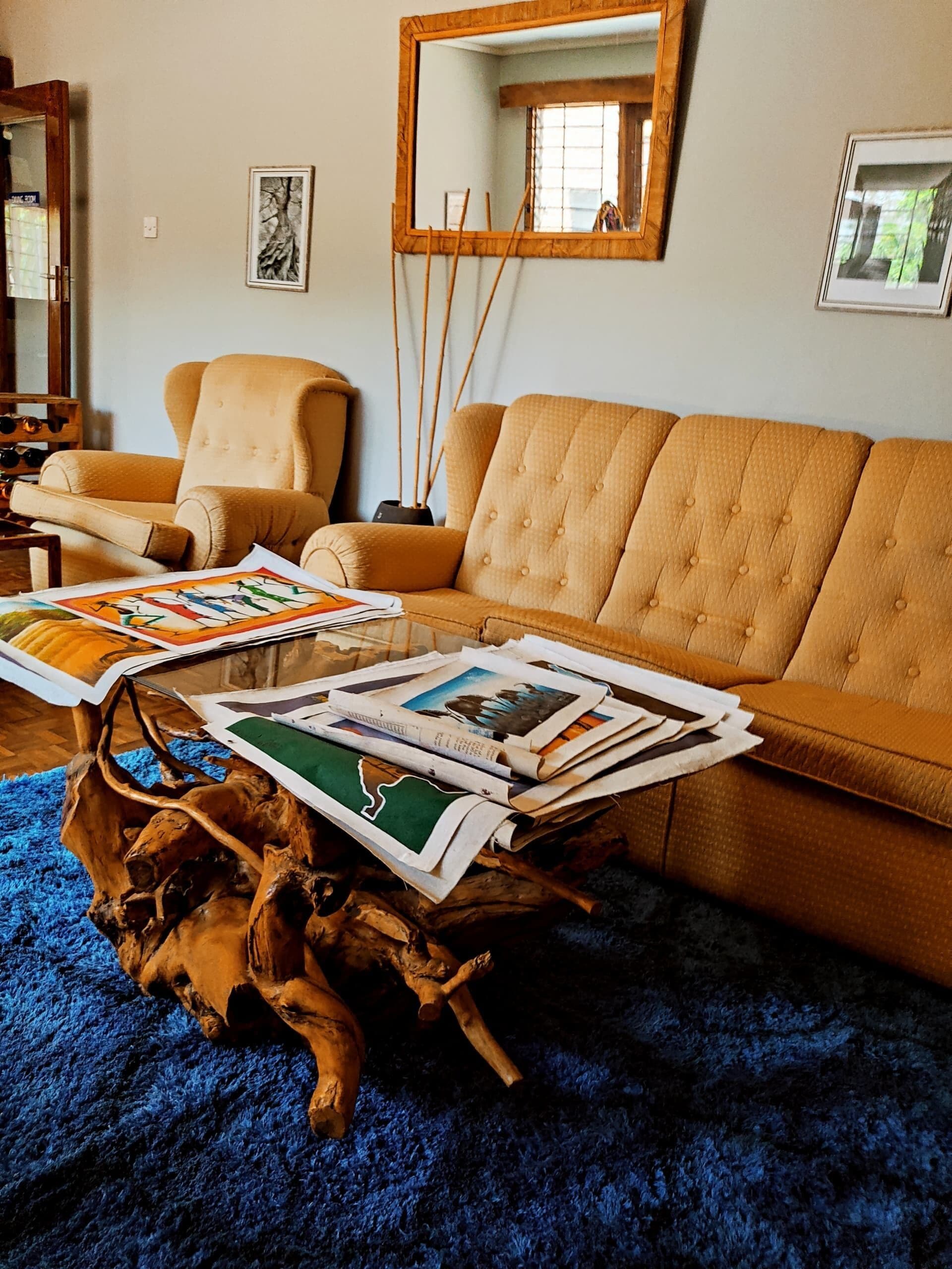 A living room with a sofa, a coffee table with magazines, a mirror, and a framed picture on the wall.