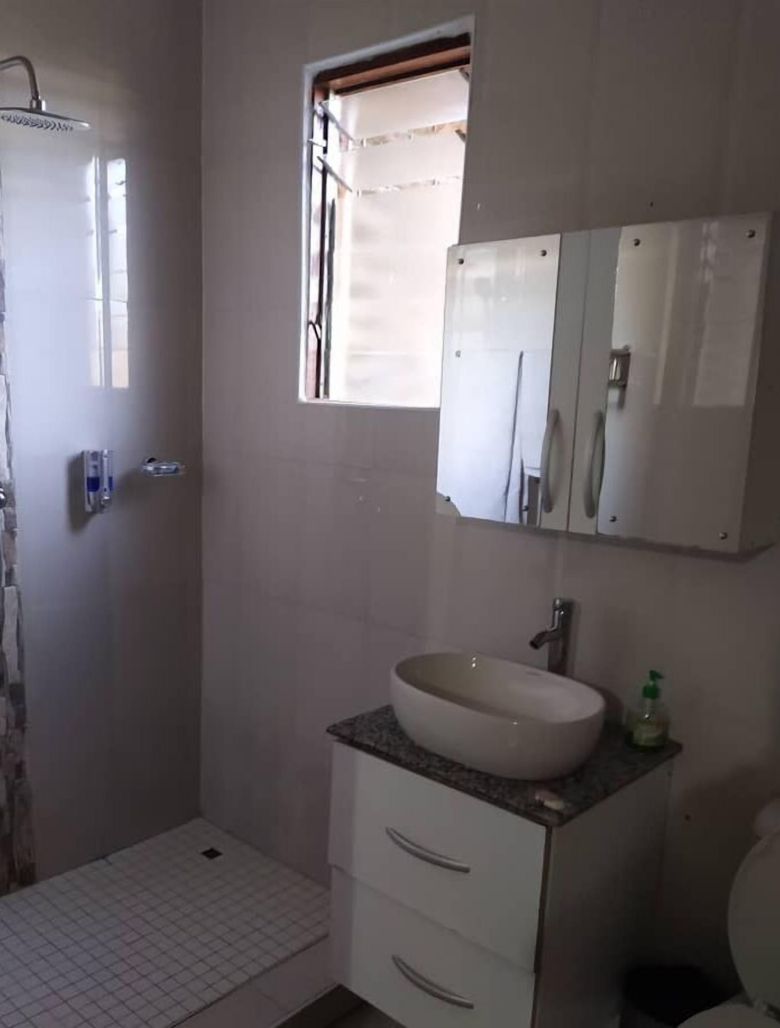 Une salle de bain avec un lavabo blanc, un miroir et une douche.