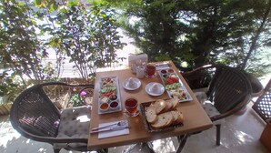 An outdoor dining table with a variety of food items and drinks, surrounded by wicker chairs. - New Beylerbeyi Hotel (Istanbul)