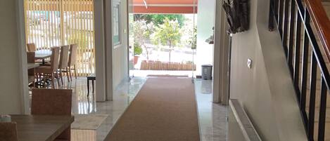A hallway with a carpet leading to a dining area with wooden furniture.