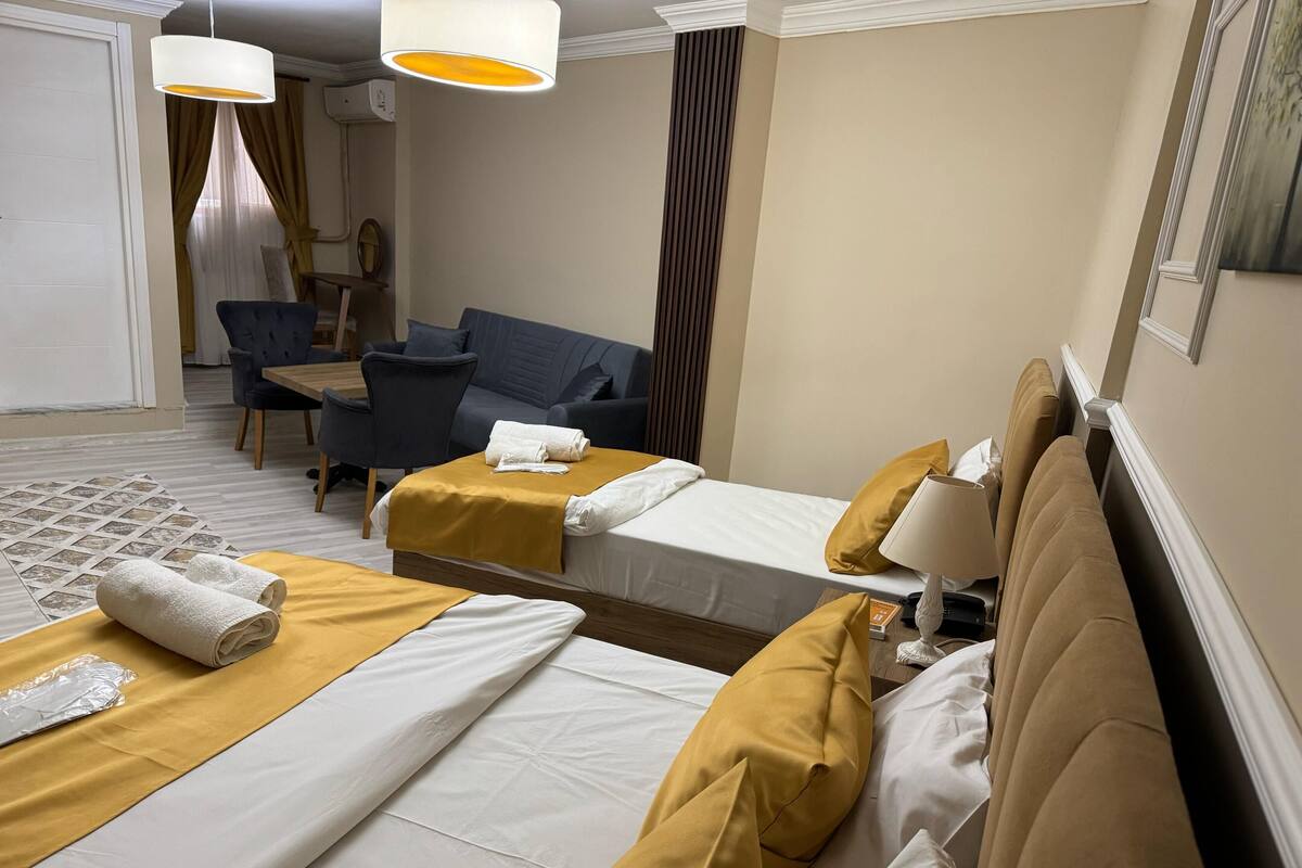 Et hotelværelse med to senge, en sofa, et spisebord og en stol.