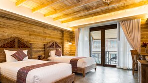 Una habitación con dos camas de madera, techo de madera y un balcón con vistas.