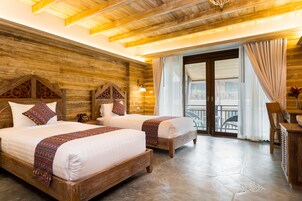A room with two wooden beds, a wooden ceiling, and a balcony with a view.