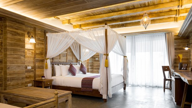 Un espacioso dormitorio con cama con dosel, paredes de madera y un gran ventanal.