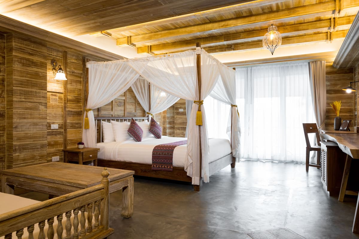 Un espacioso dormitorio con cama con dosel, paredes de madera y un gran ventanal.