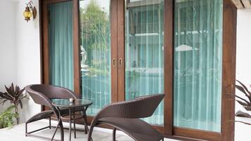 A glass door leading to a patio with wicker furniture and a small table.