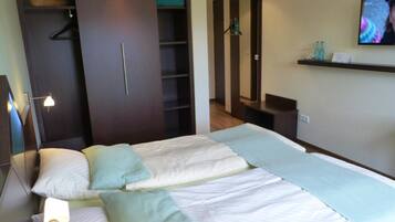 Ein Hotelzimmer mit Bett, Schrank, Fernseher und einer Ablage mit Flaschen.