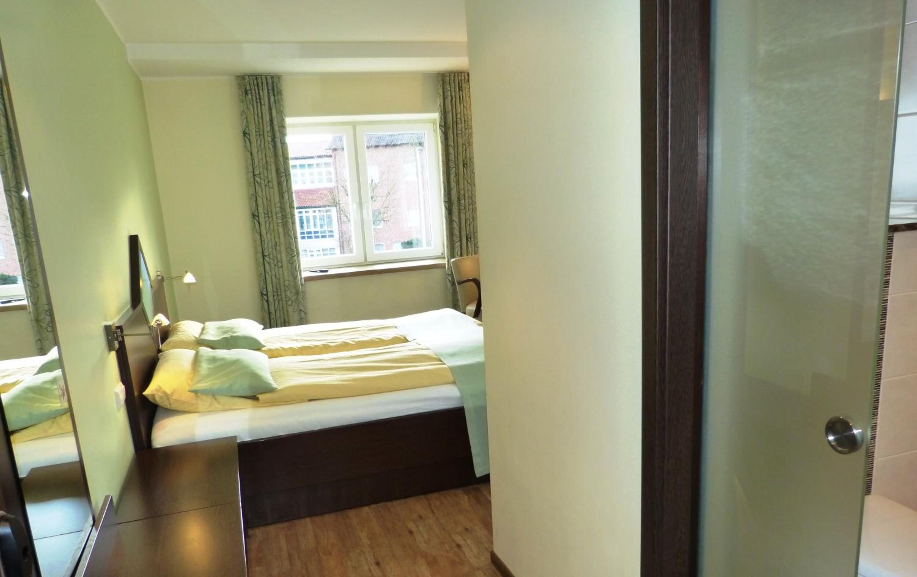 A bedroom with a bed, a window, and a door.