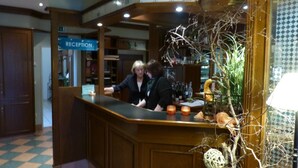 A reception area with a reception desk, a reception sign, and a potted plant. - Hotel Landgasthof Evering (Emsbueren)