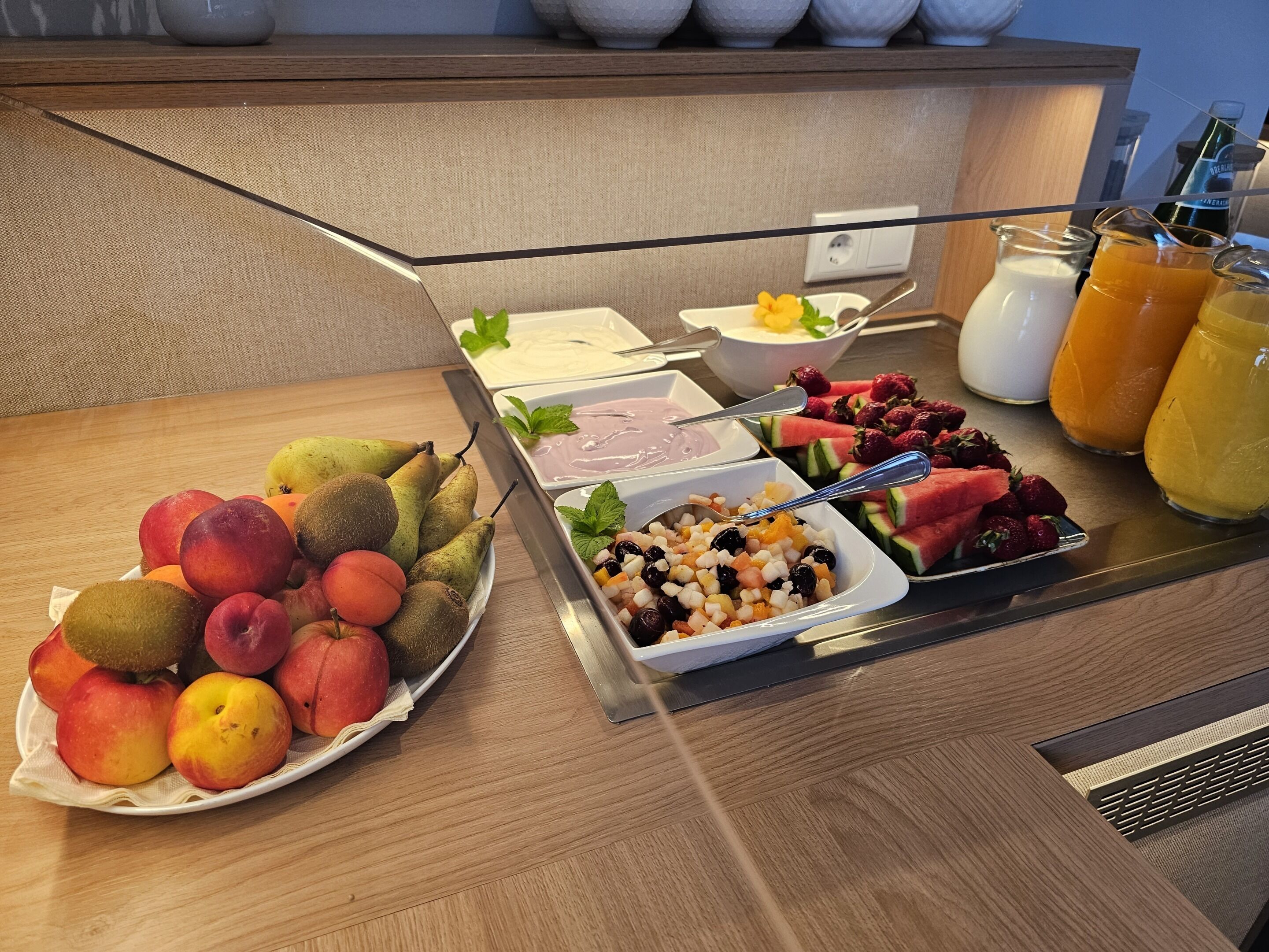A breakfast buffet with various fruits, yogurt, and juices.