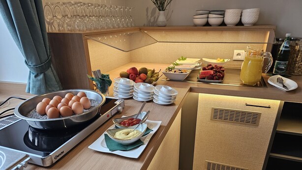 Preparación de un bufé de desayuno con huevos, frutas y bebidas.