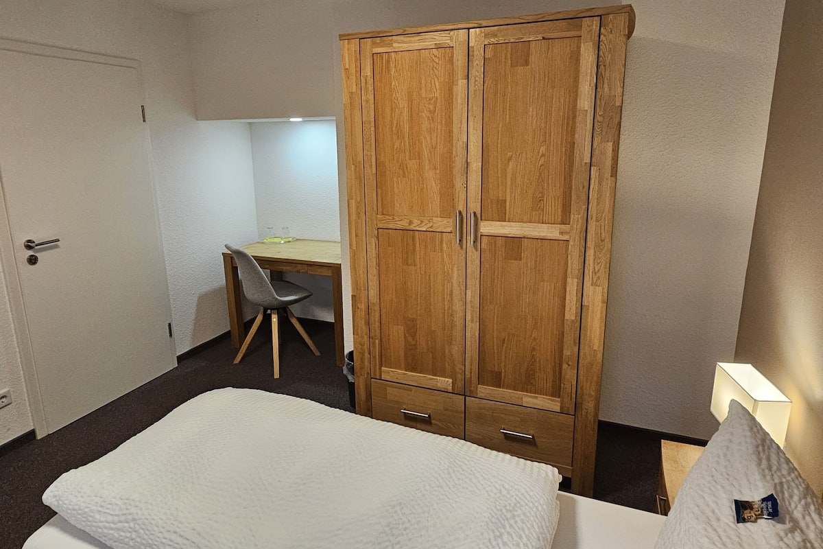Ein Schlafzimmer mit Bett, Schreibtisch und Kleiderschrank.