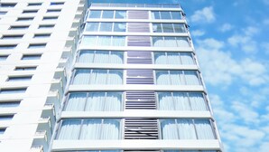 Un edificio de varios pisos con un cartel que dice 'PRAGUE HOTEL' y un banderín que anuncia 'APERTURA 15/06/2023'.