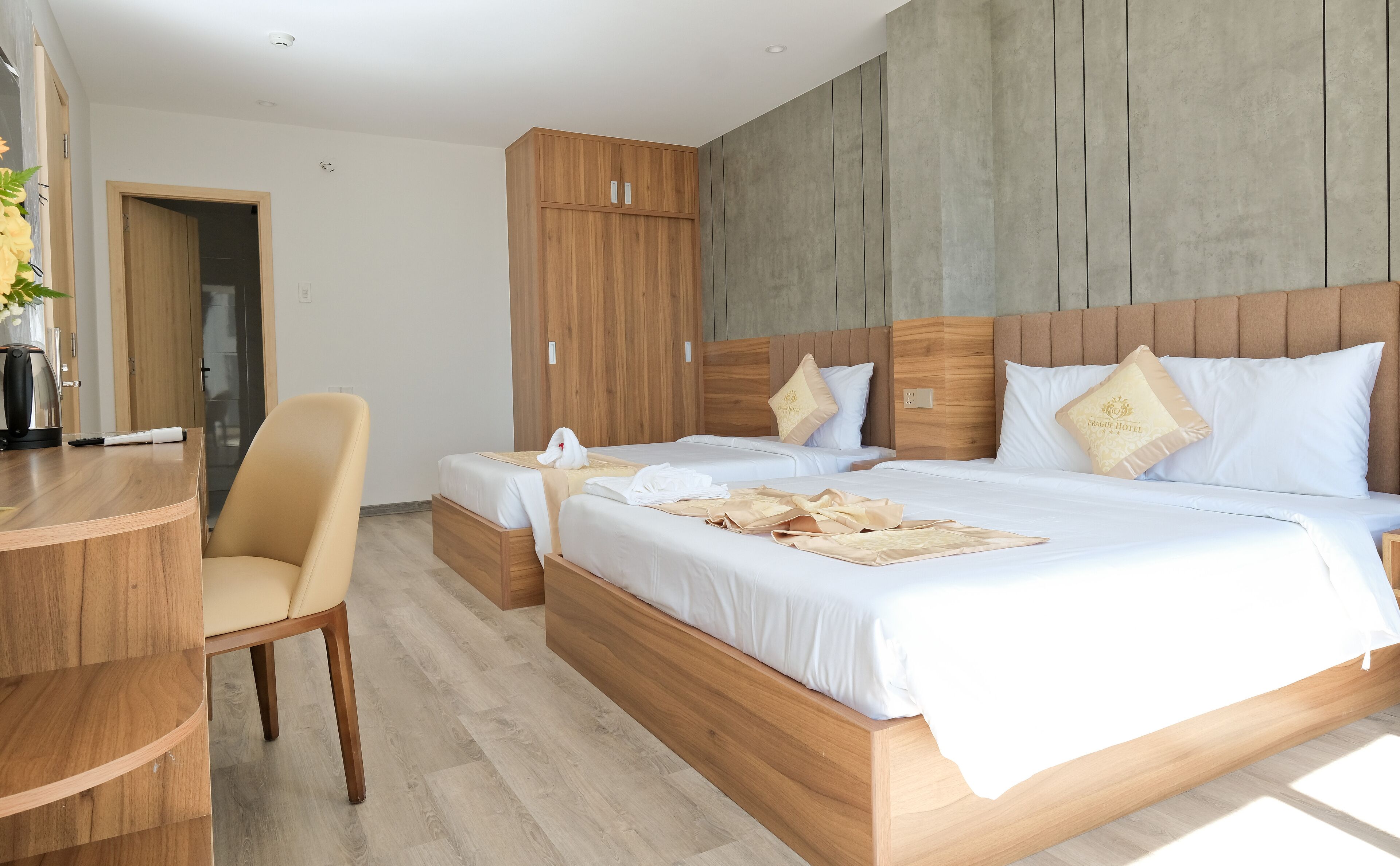 A hotel room with two beds, wooden headboards, and a desk with a chair.
