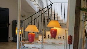 A staircase with two lamps, a bookshelf, and a small statue collection. - Landhotel Burkartsmühle (Hofheim am Taunus)