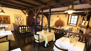A restaurant with wooden beams, white tablecloths, and candlelit ambiance. - Landhotel Burkartsmühle (Hofheim am Taunus)