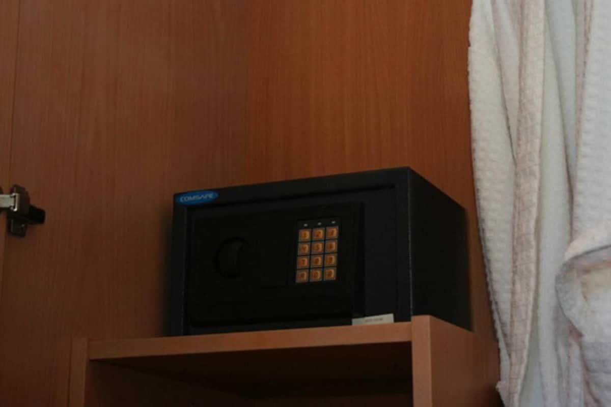 A black Compaq computer on a wooden shelf in a room with a wooden door and a white towel hanging on the right.