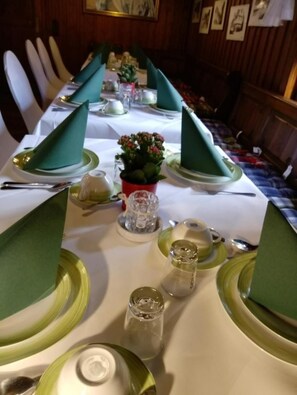 A dining table set for a meal with green napkins, plates, and glassware. - Landhotel Burkartsmühle (Hofheim am Taunus)