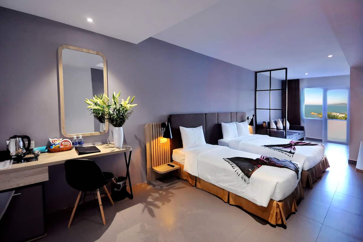 Une chambre d’hôtel moderne dotée d’un grand lit, d’un bureau, d’une chaise, d’un miroir et offrant une vue sur la ville.