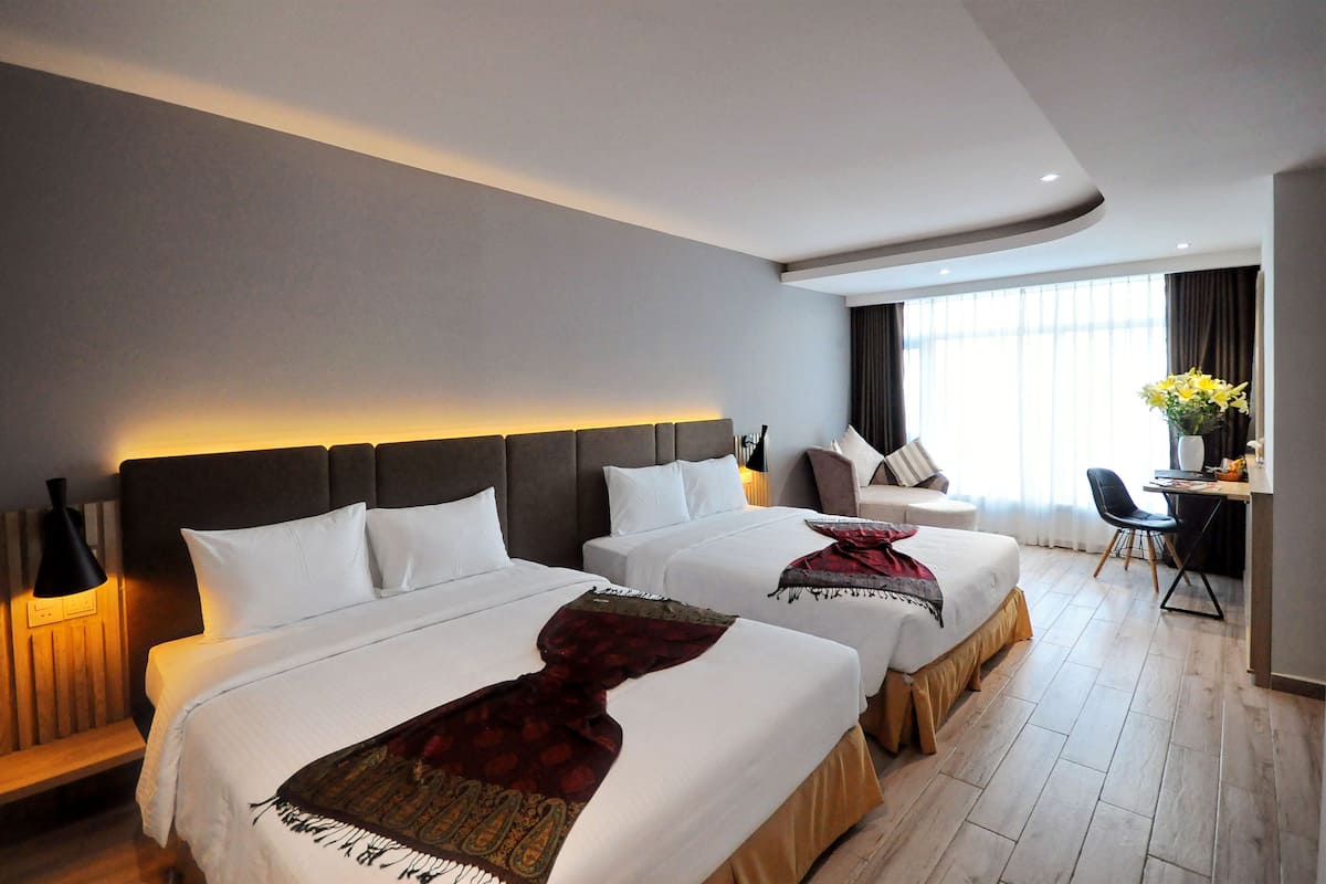 Une chambre d’hôtel avec deux lits, un bureau et une chaise.