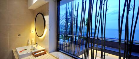 A modern bathroom with a large window, a bathtub, and a mirror.