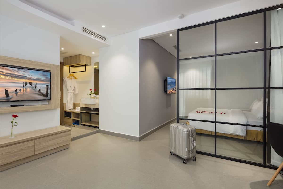 Une chambre d’hôtel moderne avec un grand lit, une télévision, une armoire et une valise.