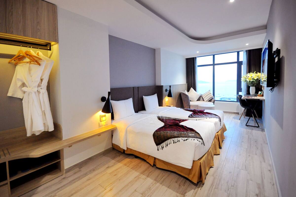 Une chambre d’hôtel avec deux lits, un bureau, une télévision et une fenêtre donnant sur un paysage agréable.