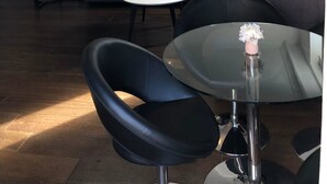 Ein modernes Wohnzimmer mit einer Eckcouch, einem Glastisch und einem runden Esstisch.