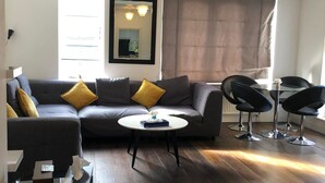 Ein modernes Wohnzimmer mit einem grauen Sofa, einem runden Couchtisch und schwarzen Stühlen.